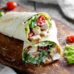 Chicken Caesar Salad Wrap sliced in half on wooden board