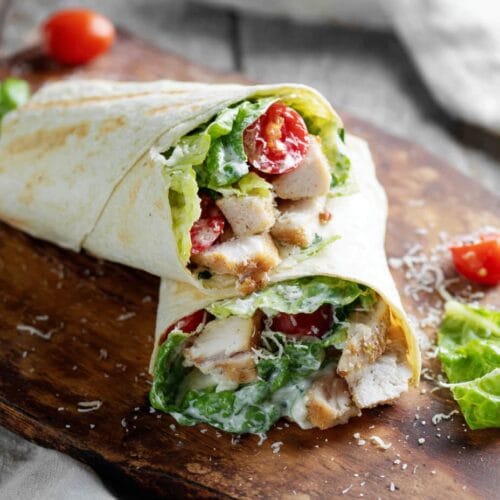Chicken Caesar Salad Wrap (The Best Easy Lunch You’ll Crave Again) 3 Chicken Caesar Salad Wrap sliced in half on wooden board