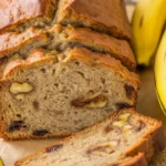 Moist Banana Bread with Walnuts and Chocolate Chips on a wooden table.