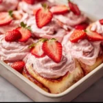 Freshly baked strawberry cinnamon rolls with glaze on a wooden table