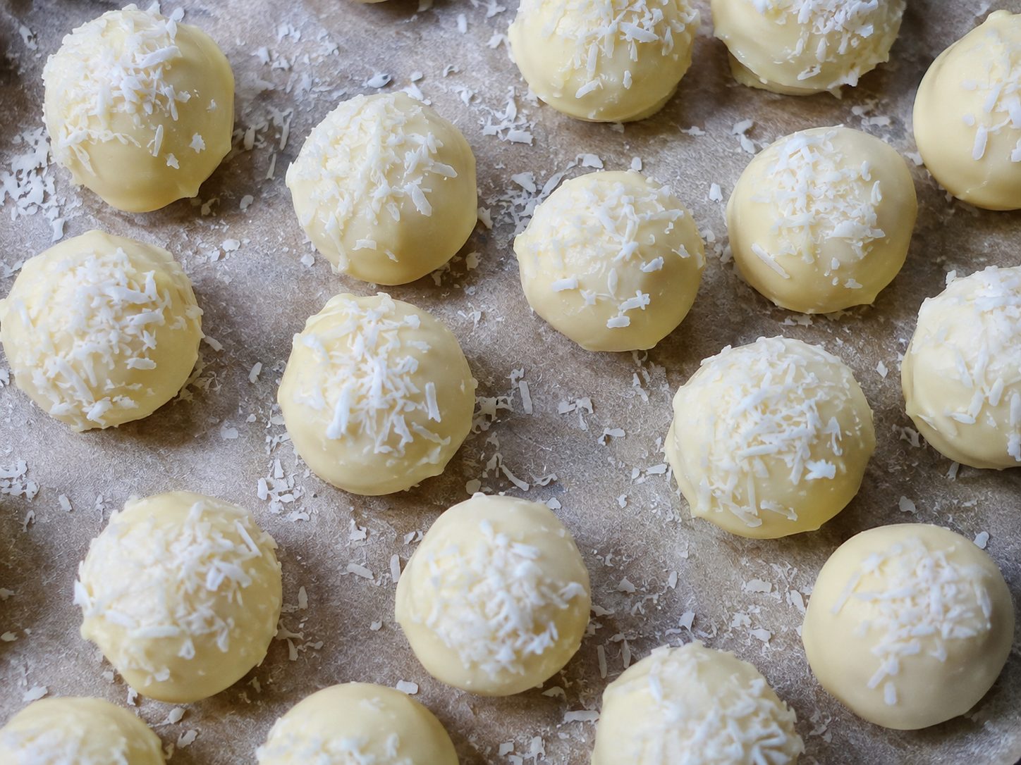 3-Ingredient Coconut Snowball Truffles coated in white chocolate and topped with shredded coconut