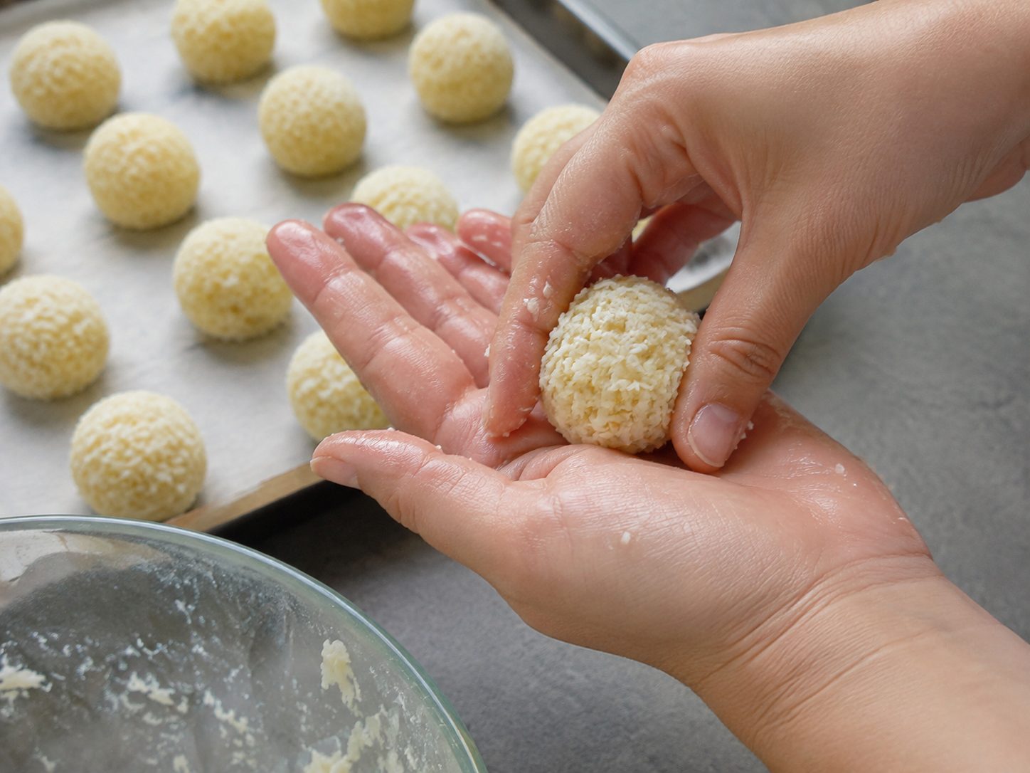 3-Ingredient Coconut Snowball Truffles: A No-Bake Treat You Roll, Freeze, and Dip 2 Hands rolling desiccated coconut and condensed milk mixture into a ball for coconut snowball truffles