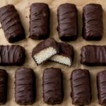 Dark chocolate coconut candy bars on parchment paper with one bar cut in half